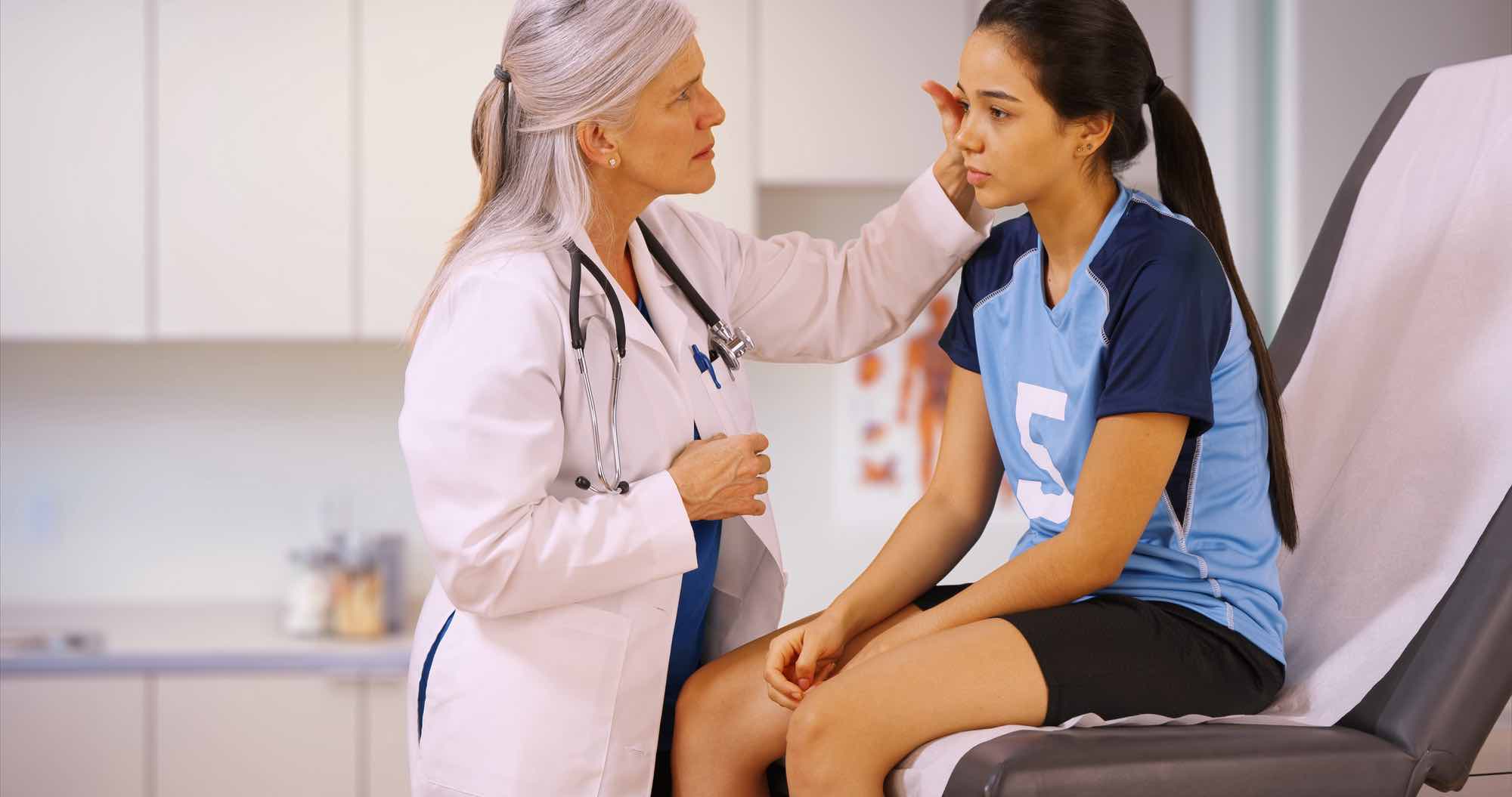 Doctor examining child student athlete in high school