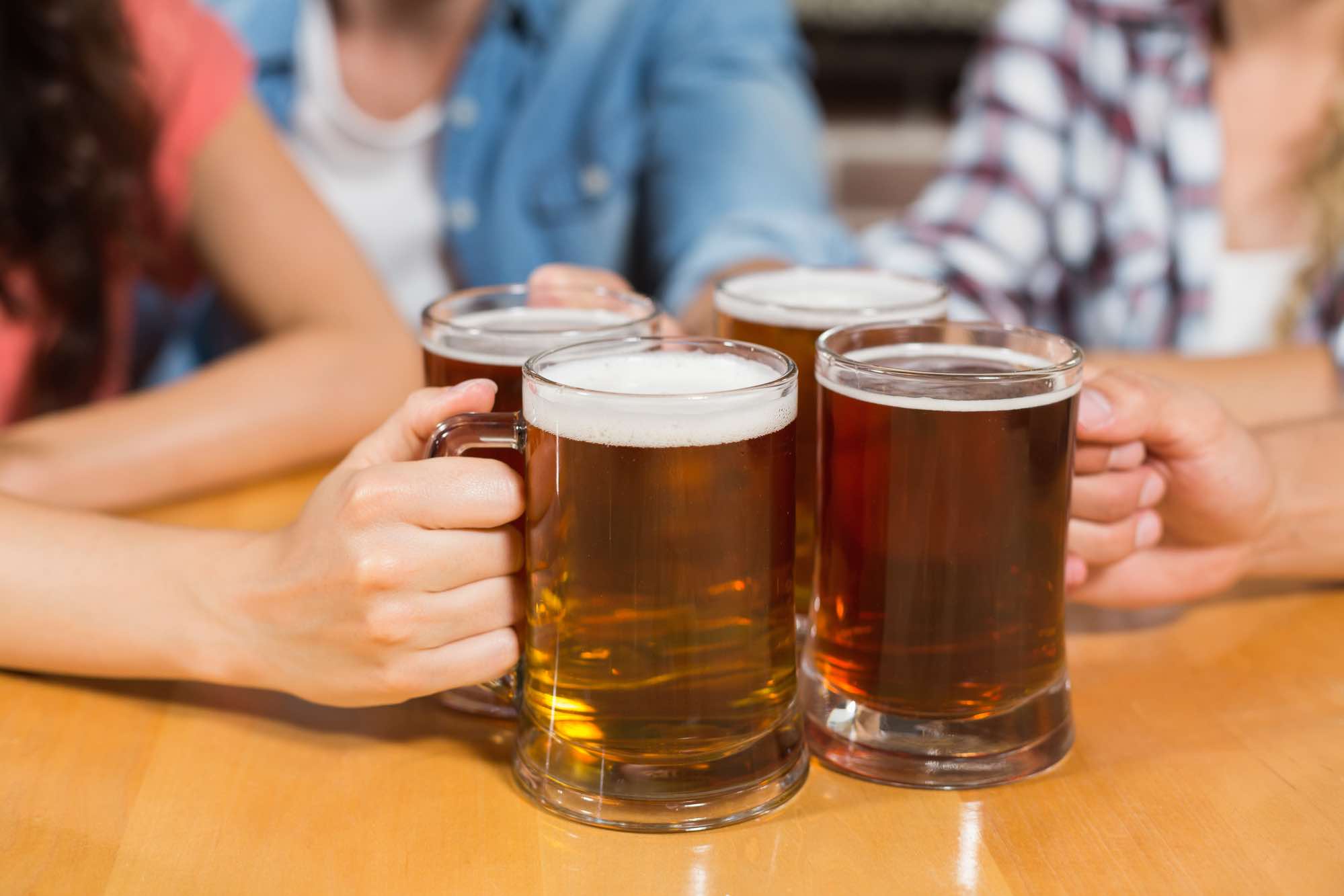 Friends toasting cheers with beers at bar